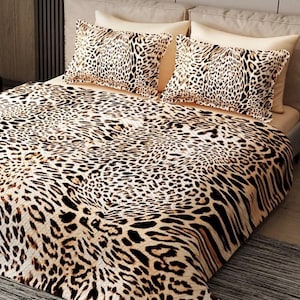 Puede incluir: Juego de cama con estampado de leopardo. El conjunto incluye una manta y dos fundas de almohada. El dise&ntilde;o presenta manchas negras sobre un fondo beige. La ropa de cama est&aacute; colocada sobre una cama con cabecero de color neutro.