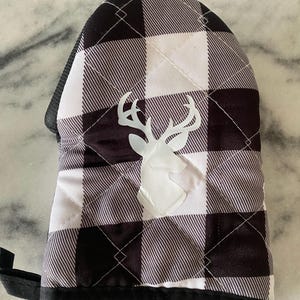 May include: Black and white buffalo check oven mitt with a white deer head silhouette. The mitt has a black trim and a loop for hanging. The quilted design adds a decorative touch to this kitchen accessory.