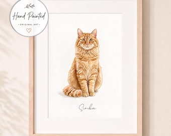 Op de afbeelding: Een ingelijst aquarelportret van een langharige oranje cyperse kat die rechtop zit. De kat heeft gouden ogen en een gedetailleerde vachtstructuur. Onder de kat staat de naam Simba in zwarte letters. Een ronde badge vermeldt Hand Painted Original Art.