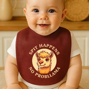 May include: A smiling baby wearing a maroon bib with the text "SPIT HAPPENS NO PROBLAMA" around a cartoon llama. The llama is light brown with a yellow circle background. The baby is wearing a white onesie.