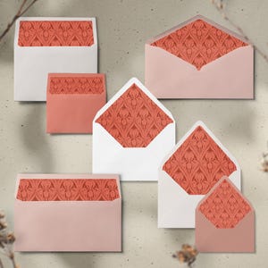 May include: A collection of envelopes in various sizes and colors, including white and blush pink. Each envelope features a coral-colored floral pattern lining the interior. The envelopes are arranged on a neutral background.