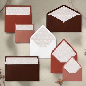 May include: An assortment of envelopes in various sizes and shades of brown and red. The envelopes have a white patterned interior. Some envelopes are open, revealing the patterned lining. The envelopes are arranged on a neutral background.