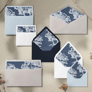 May include: An assortment of envelopes in various sizes and colors, including light blue, white, and navy. Each envelope features a dark blue interior with a white tree design. The envelopes are arranged on a neutral background.