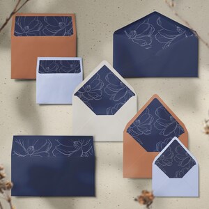 May include: An assortment of envelopes in various sizes and colors, including navy blue and terracotta. Each envelope features a white floral design on the interior lining. The envelopes are arranged on a neutral background.