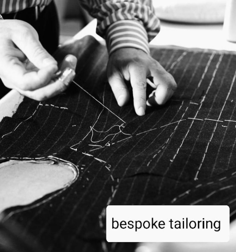 May include: A monochrome image showing a tailor sewing pinstripe fabric. The tailor's hands are visible, working with a needle and thread. The text "bespoke tailoring" is displayed in a white box at the bottom of the image.
