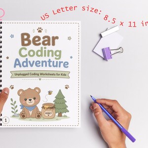 Può includere: Un quaderno a spirale intitolato "Bear Coding Adventure" con un'illustrazione di orso dei cartoni animati. Il quaderno misura 21,6 x 27,9 cm. La copertina presenta il testo "Unplugged Coding Worksheets for Kids". Una penna viola è tenuta vicino.
