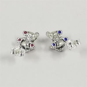 Pu&ograve; includere: Un paio di orecchini a lobo argentati a forma di orsetto, con dettagli rossi e blu. Gli orecchini sono contrassegnati con "PANDORA S925 ALE Disney".