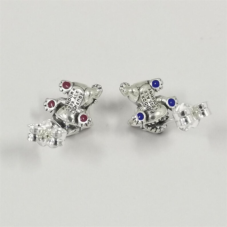 Pu&ograve; includere: Un paio di orecchini a lobo argentati a forma di orsetto, con dettagli rossi e blu. Gli orecchini sono contrassegnati con "PANDORA S925 ALE Disney".
