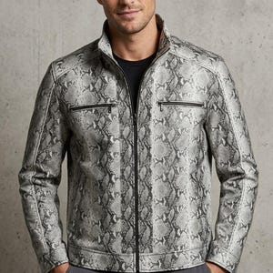 Peut inclure: Une veste à motif peau de serpent argenté et noir avec un col montant, une fermeture éclair frontale intégrale et deux poches de poitrine horizontales zippées. La veste présente des manches longues avec des poignets zippés sur un t-shirt noir.