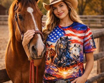 May include: A woman wearing a straw cowboy hat and a graphic t-shirt featuring the American flag and horses. She is standing next to a brown horse in a corral. The shirt has a sunset and mountain scene.