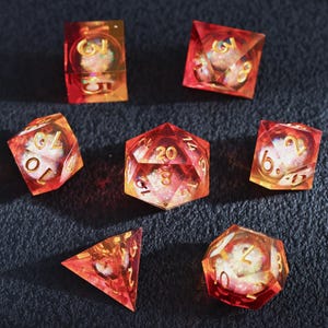 Conjunto de dados de resina com núcleo líquido vermelho-alaranjado, bordas afiadas e números dourados, conjunto de 7 peças poliédricas com glitter para D&D.