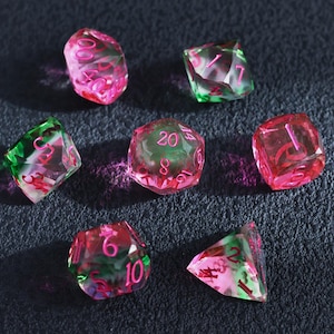 Conjunto de dados com núcleo líquido rosa e verde, resina transparente com números rosa, 7 dados poliédricos com bordas afiadas para D&D