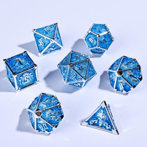Op de afbeelding: Een set van zeven blauwe en zilverkleurige polyhedrale dobbelstenen. Elke dobbelsteen heeft een blauw oppervlak met zilveren accenten en cijfers. De dobbelstenen hebben verschillende geometrische vormen, waaronder een kubus, een piramide en een dodecaëder. Voor tabletopspellen.