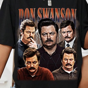 May include: Black t-shirt with a graphic of Ron Swanson and the text "RON SWANSON" in orange and blue. The graphic includes multiple images of the character. The shirt is a short-sleeved crew neck.