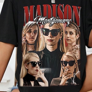 Peut inclure: T-shirt noir avec un graphisme représentant une femme portant des lunettes de soleil, avec le nom "MADISON MONTGOMERY" en texte rouge et blanc. Le design comprend plusieurs images de la même femme. Le t-shirt a des manches courtes.