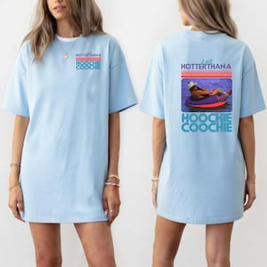 May include: Light blue t-shirt with the text "HOTTERTHANA HOOCHIE COOCHIE" on the front. The back of the shirt features a graphic of a person in a tube with the text "It gets HOTTERTHANA HOOCHIE COOCHIE".
