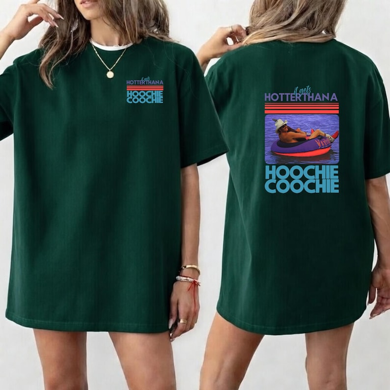 May include: Dark green t-shirt with the text "HOTTERTHANA HOOCHIE COOCHIE" on the front and back. The back of the shirt features a graphic of a person in a tube on the water. The shirt is a casual, oversized style.