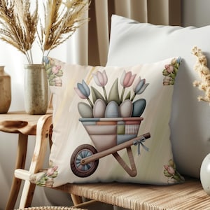 Può includere: Cuscino decorativo con un design a carriola pastello pieno di uova di Pasqua e tulipani. Il cuscino ha uno sfondo chiaro con accenti floreali ed è posto su una panca di legno. Il design include elementi blu, rosa e verdi.