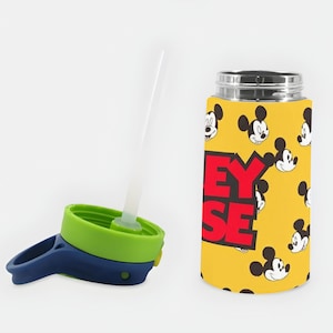 Puede incluir: Una botella de agua amarilla con un patr&oacute;n repetitivo de caras de Mickey Mouse y el texto Mickey Mouse en letras rojas grandes. La botella tiene una tapa separada con un tap&oacute;n de rosca verde lima, un asa azul oscuro y una pajita de pl&aacute;stico.