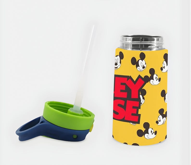 Puede incluir: Una botella de agua amarilla con un patr&oacute;n repetitivo de caras de Mickey Mouse y el texto Mickey Mouse en letras rojas grandes. La botella tiene una tapa separada con un tap&oacute;n de rosca verde lima, un asa azul oscuro y una pajita de pl&aacute;stico.