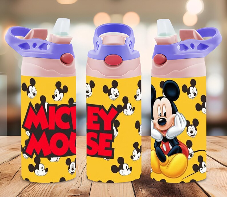 Puede incluir: Una botella de agua amarilla con un patr&oacute;n repetitivo de cabezas de Mickey Mouse y el texto MICKEY MOUSE en letras rojas negritas. La botella tiene un cuello rosa claro, una tapa morada con asa y una boquilla de pajita abatible transparente.