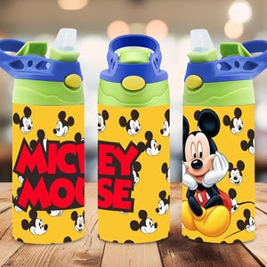Puede incluir: Una botella de agua amarilla con un patr&oacute;n repetitivo de Mickey Mouse, el texto MICKEY MOUSE en letras rojas grandes y un gr&aacute;fico m&aacute;s grande de Mickey Mouse. La tapa azul y verde lima tiene una boquilla de pl&aacute;stico transparente y un asa.