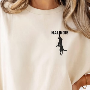 May include: A white ceramic mug with a black handle and the text "But first, coffee" in a black, handwritten-style font. The mug is on a white surface.