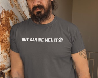 May include: A dark grey short-sleeved t-shirt featuring the white text "BUT CAN WE MEL IT" followed by a white graphic icon of a gear containing a wrench. The shirt has a crew neckline and a standard fit, displaying a clean and simple design.