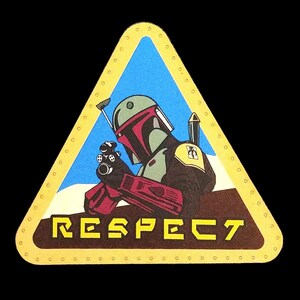 Op de afbeelding: Een driehoekige leren patch met een gele rand en een blauwe achtergrond. De patch heeft een cartoonafbeelding van Boba Fett uit Star Wars die een blastergeweer vasthoudt. De tekst "RESPECT" is in gele letters onderaan de patch gedrukt.