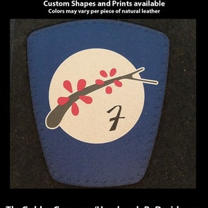 May include: A blue leather patch with a white circle containing a black branch with red blossoms and the number 7. The text "Hand Printed Leather Patches" is at the top of the image. The text "Custom Shapes and Prints available" is below the first line of text. The text "Colors may vary per piece of natural leather" is below the second line of text. The text "TheGoldenGear.com/HandmadeByDroids.com" is at the bottom of the image.