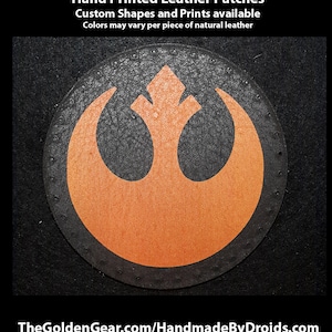 May include: A hand-printed leather patch featuring the Rebel Alliance symbol in orange and black. The patch is circular and has a distressed look. The text "TheGoldenGear.com/HandmadeByDroids.com" is visible at the bottom of the image.