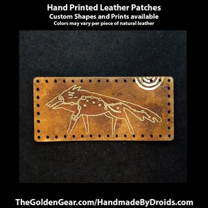 Pu&ograve; includere: Toppa in pelle stampata a mano con un lupo stilizzato e dettagli di costellazioni. La toppa rettangolare marrone presenta un disegno color oro. Il testo "Hand Printed Leather Patches" &egrave; in alto. Sono disponibili forme e stampe personalizzate.