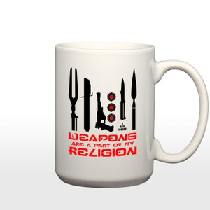 May include: White ceramic mug with a black silhouette of various weapons and the text "WEAPONS ARE A PART OF MY RELIGION" in red.