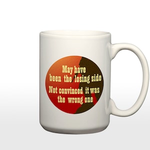 May include: White ceramic coffee mug with a red, orange, and brown circle graphic. The graphic features a silhouette of a person and the text "May have been the losing side Not convinced it was the wrong one".