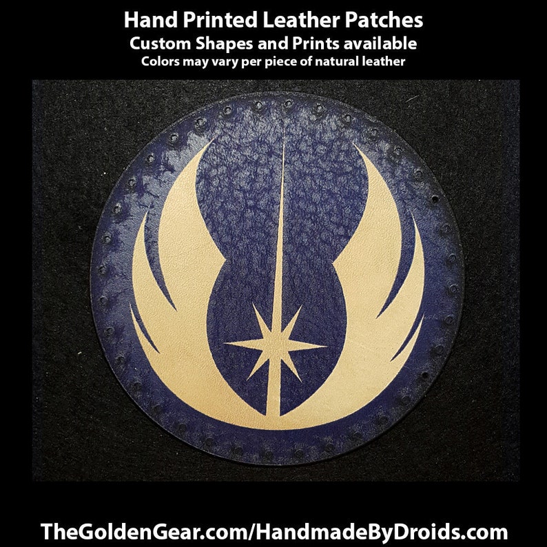 May include: A round, blue leather patch with a gold-coloured Star Wars Rebel Alliance symbol. The patch has a stitched edge.