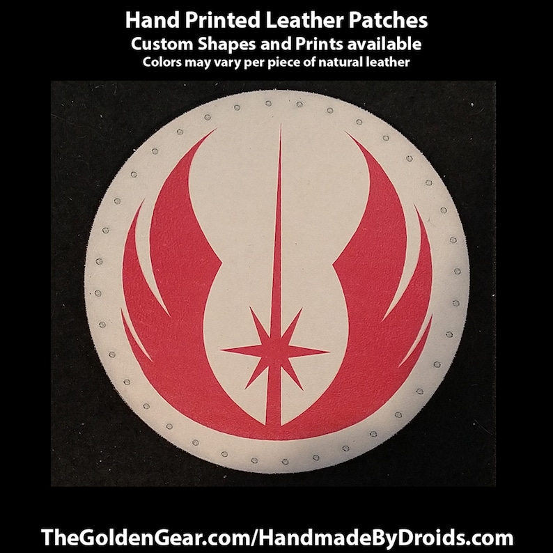 May include: A round, white leather patch with a red and white symbol. The symbol is a stylised representation of a lightsaber with wings. The patch is surrounded by a circle of small holes.