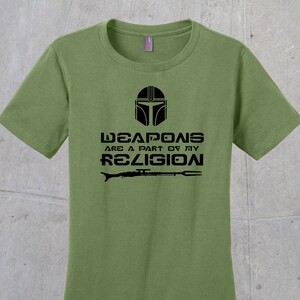 May include: A green t-shirt with a black graphic of a Mandalorian helmet and the text "Weapons are a part of my religion".