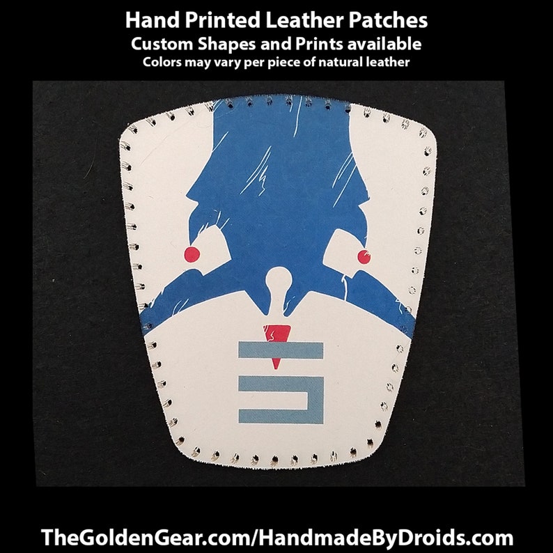 Puede incluir: Un parche de cuero blanco con un dise&ntilde;o azul y rojo. El parche tiene una letra estilizada "E" en el centro y una forma azul encima. El texto "Hand Printed Leather Patches" est&aacute; en la parte superior de la imagen. El texto "Custom Shapes and Prints available" est&aacute; debajo de la imagen. El texto "Colors may vary per piece of natural leather" est&aacute; debajo de la segunda l&iacute;nea de texto.