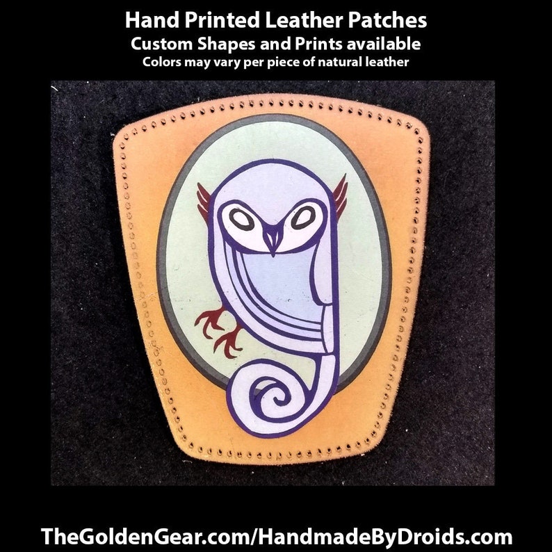 May include: A hand-painted leather patch featuring a stylized owl with purple, blue, and green accents. The patch is surrounded by a stitched border and has a light brown background.