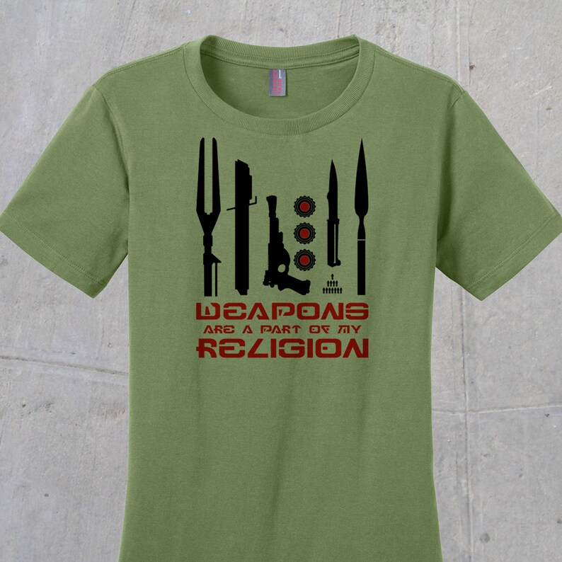 May include: A green t-shirt with a black graphic of various weapons and the text "WEAPONS ARE A PART OF MY RELIGION" in red.