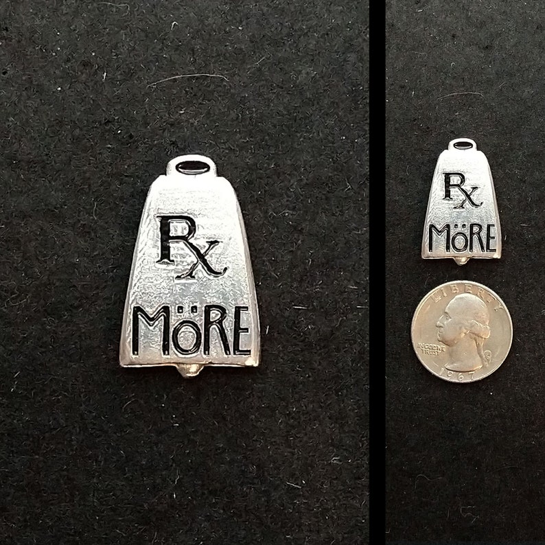 May include: A silver bell charm with the words "Rx More" engraved on it. The bell is about the size of a quarter.
