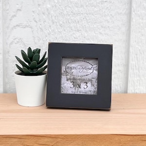 Puede incluir: Un marco de fotos de madera negro con una abertura de 7,62 x 7,62 cm. El marco está hecho a mano en los Estados Unidos y tiene un diseño rústico. El texto "Rustic Refined Design" es visible en el marco.