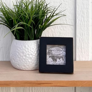 Puede incluir: Un marco de fotos de madera negro con una etiqueta blanca que dice "Rustic Designs Handmade in USA 3 x 3 Solid Wood".