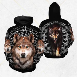 May include: Black hooded sweatshirt with a detailed wolf design. The front features a wolf with blue eyes, surrounded by smaller wolf faces and a white circular pattern. The back shows a snarling wolf within a similar design.