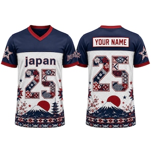 May include: A navy blue and white V-neck jersey featuring the word japan, the number 25, a red sun, Mount Fuji, and a pagoda. The back displays the text YOUR NAME above the number 25. The design includes cherry blossom and geometric patterns.