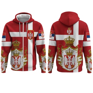 Pode incluir: Um casaco com capuz e fecho de correr vermelho e branco com o brasão de armas sérvio, apresentando uma águia de duas cabeças e uma coroa. O design inclui um padrão de cruz branca, emblemas da bandeira sérvia nas mangas e um brasão central.