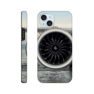 May include: A phone case featuring a high-resolution graphic of a large jet engine turbine with black blades and a silver rim. The design includes a small white spiral symbol at the center of the turbine, set against a light sky and ground.