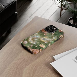 Close rear view of the green koi fish phone case on light wood, showing the printed floral design, black raised edge and square camera opening.
