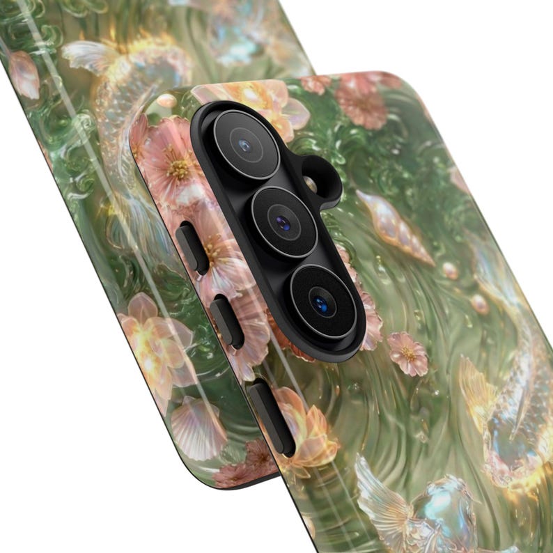Angled close-up of two green floral koi fish phone cases, showing the printed surface, raised black edges and vertical camera openings.