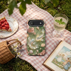 Green koi fish phone case on a pink gingham picnic cloth beside strawberry pie, a mint drink, flowers, a wicker basket and a book.
